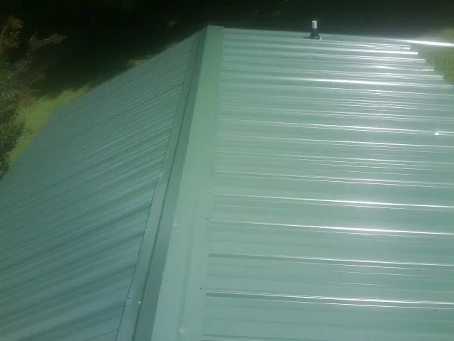 New green metal panels meeting at the ridge of a roof — Flat Roof Repair work by our crew in Fe Warren Afb