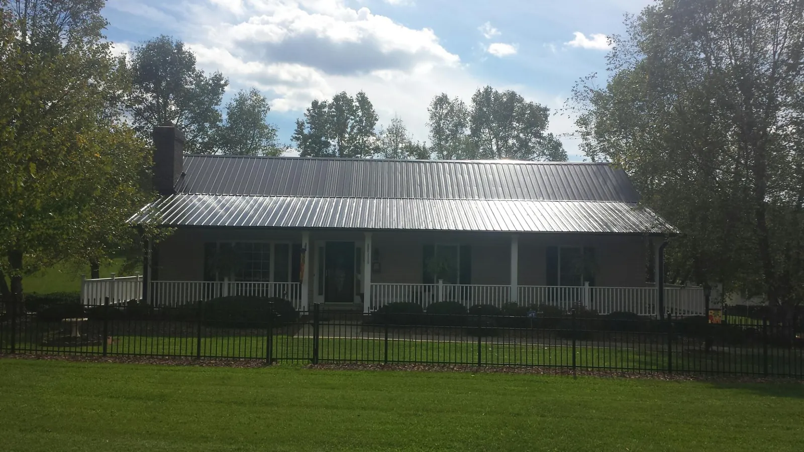 Gray metal roof on a brick ranch with a full width front porch — Gutter Guard Installation work by our crew in Fe Warren Afb