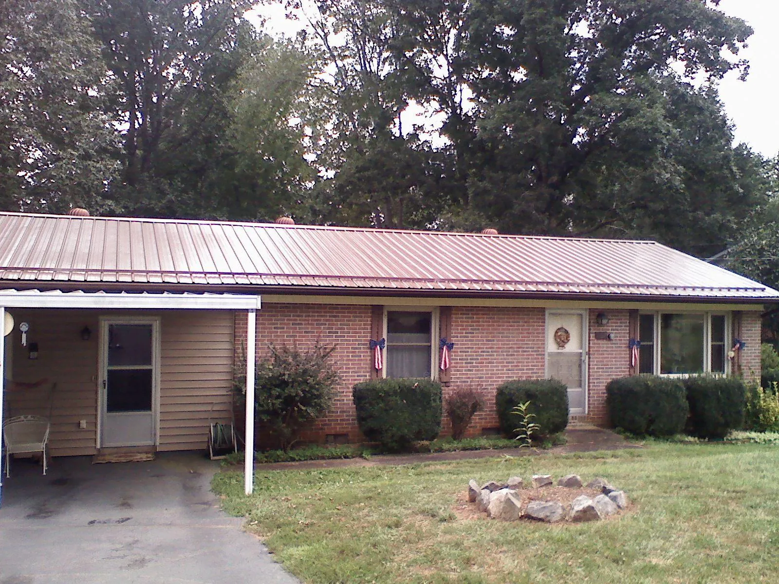 Bronze metal roof and carport on a brick ranch home — Roof Repair work by our crew in Fe Warren Afb