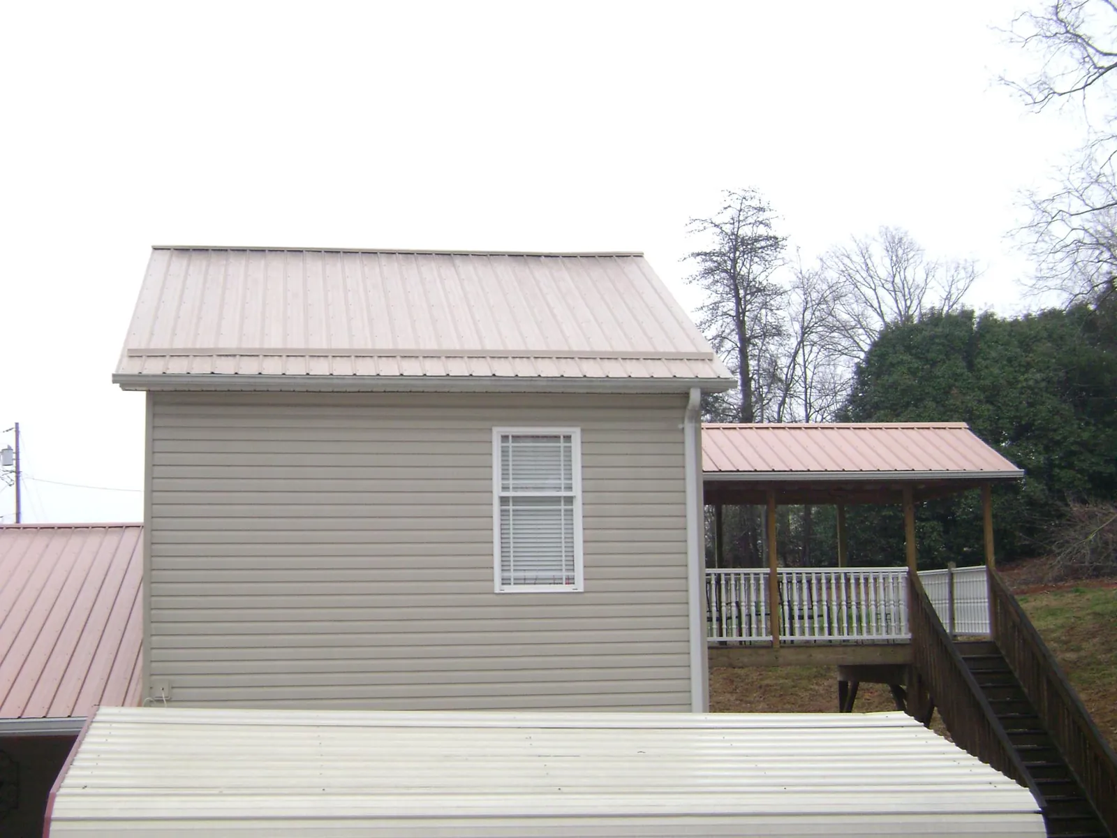 Tan metal roofs on a two story addition and attached porch, from a Roof Replacement job in Fe Warren Afb