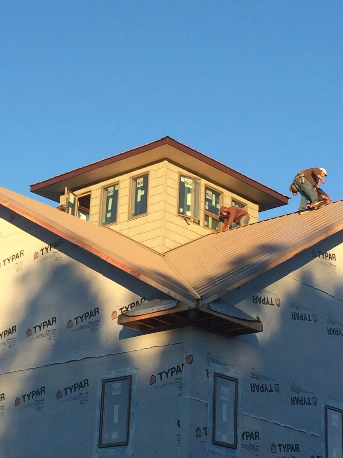 Roofers working around a rooftop cupola on a new metal roof at sunset — Roof Waterproofing in Fe Warren Afb by Roofing Brothers